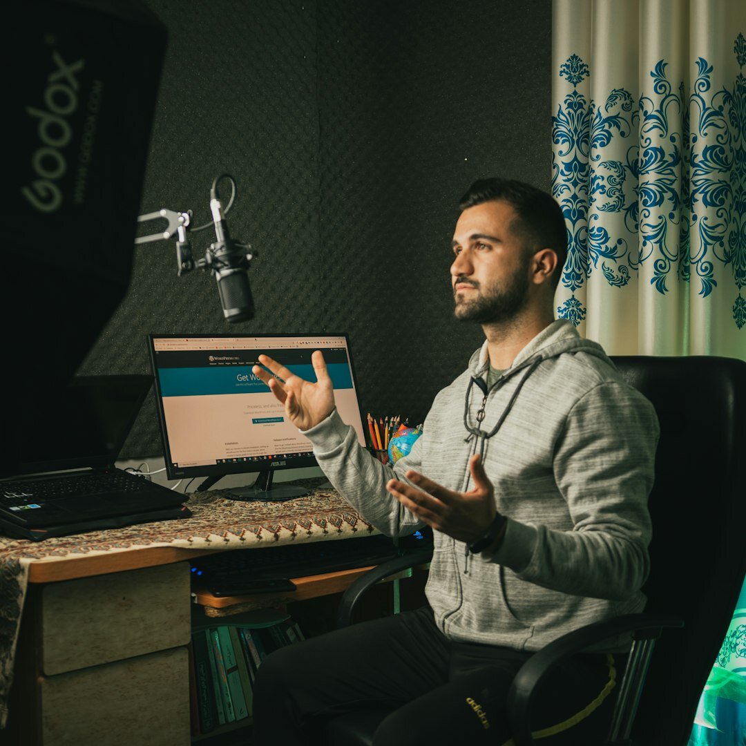 Malaysian podcast host wearing headphones speaking into a microphone in a studio