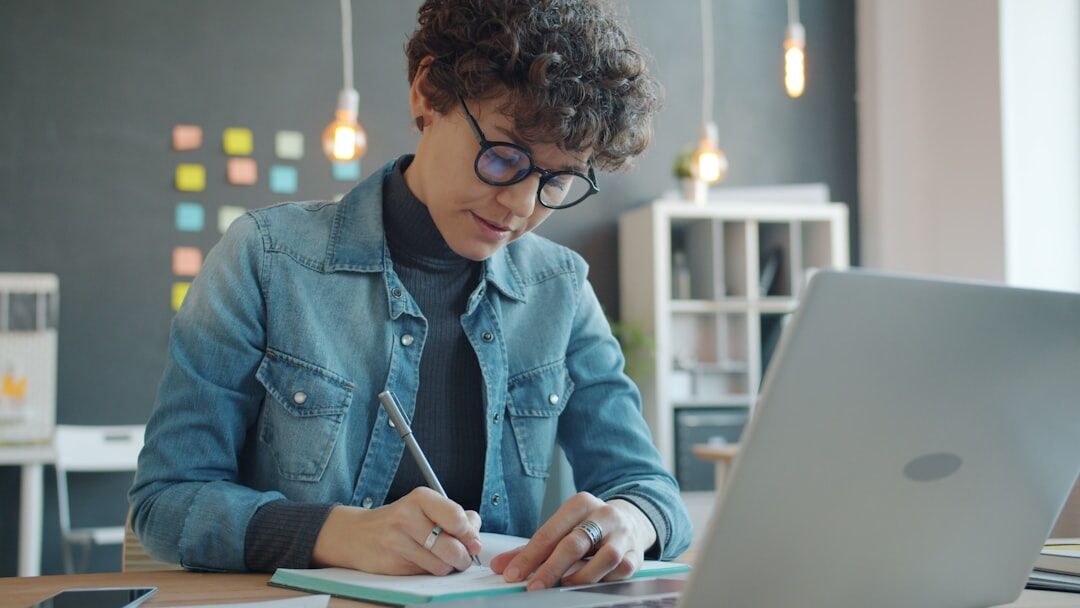 person writing in notebook at desk