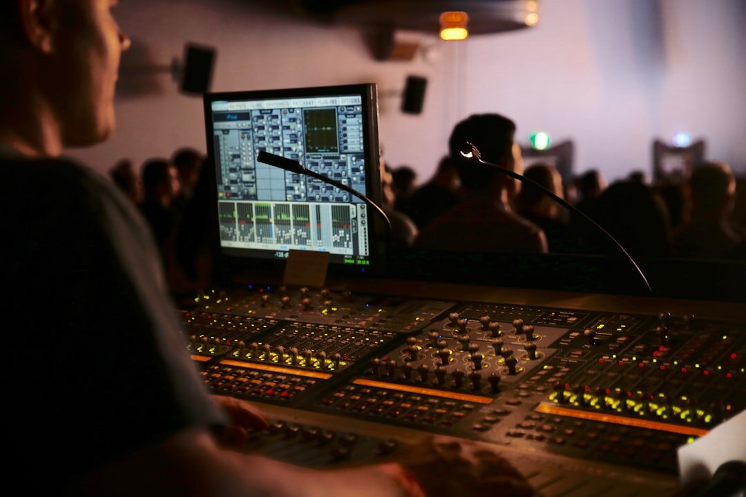 Two Malaysian audio producers reviewing a sound waveform on a laptop in a studio